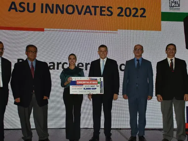 Rania Gamal on the stage receiving award (names and titles at the bottom)